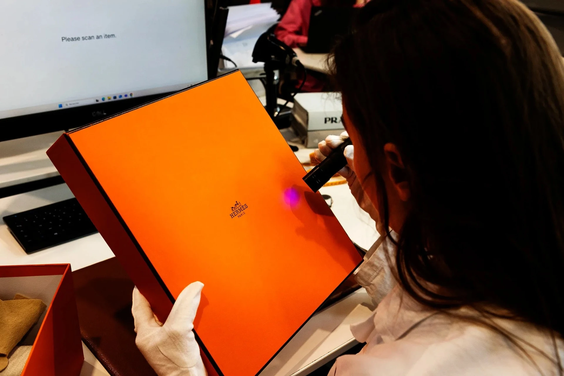 The authentication specialist examines the luxury item using a UV light.